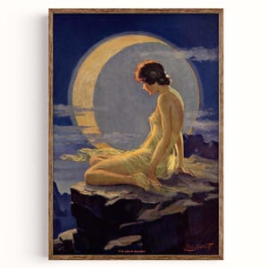 Op de afbeelding: Een ingelijste vintage kunstdruk van een vrouw in een gele jurk, zittend op een rots met een halve maan op de achtergrond. Het kunstwerk zit in een houten lijst. De titel "The Moon Maiden" is onderaan zichtbaar.