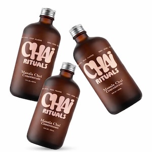 May include: Three brown glass bottles of Chai Rituals Masala Chai Concentrate. Each bottle has a silver cap and a label with the brand name and product information. The bottles are 16 fl oz / 473 ml.