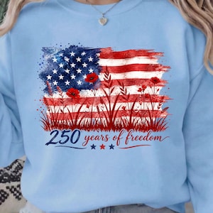 Patriotic floral USA flag PNG graphic displayed on a colorful pastel blue sweatshirt mockup.