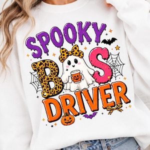 Può includere: Una felpa bianca con una stampa grafica che riporta il testo SPOOKY BOO DRIVER. Il design raffigura un fantasma con un fiocco leopardato che tiene in mano una tazza a forma di zucca, circondato da ragnatele, pipistrelli, stelle e una zucca.