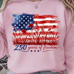 Patriotic floral USA flag PNG graphic displayed on a colorful pastel pink sweatshirt mockup.