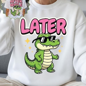 Peut inclure: Sweat-shirt blanc avec un alligator de dessin animé portant des lunettes de soleil et le mot "LATER" en lettres roses à bulles. L'alligator est vert avec un ventre blanc et des étoiles jaunes. Une petite image du motif est sur un t-shirt blanc.