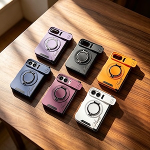 Peut inclure: Six coques de smartphone rectangulaires en violet, noir, orange, bleu foncé, bordeaux et blanc. Chaque coque présente un anneau de support circulaire, un cache coulissant pour l'objectif photo et un mot en cursive sur le panneau arrière.
