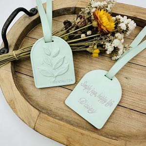 May include: A handmade wooden sign with the text "Welcome to our home" in a handwritten style. The sign is painted white with a distressed finish, and a small, decorative heart is attached. The sign measures approximately 30 cm wide.