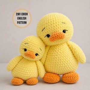May include: Two yellow crocheted chick plush toys with orange beaks and feet, black eyes, and stitched eyebrows. A circular graphic in the upper left corner contains the text 2IN1 CHICK ENGLISH PATTERN. The toys have a soft, textured yarn finish.
