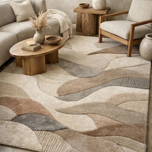 Puede incluir: Una alfombra grande con un diseño ondulado y texturizado en tonos beige, marrón y gris. La alfombra está colocada en un salón con un sofá, una mesa de centro y un sillón. Las dimensiones de la alfombra son de aproximadamente 244 x 305 cm.