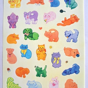 Puede incluir: Hoja de pegatinas vintage de Hallmark con gatos y perros de dibujos animados coloridos. Las pegatinas incluyen varias poses y colores, como naranja, azul, verde y morado. Algunas pegatinas tienen lazos, corazones y otros elementos decorativos.