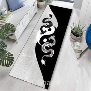 May include: A long, rectangular rug with a yin-yang design and two dragons. One dragon is black, the other white. The rug has a black and white colour scheme and is on a light-coloured wooden floor.