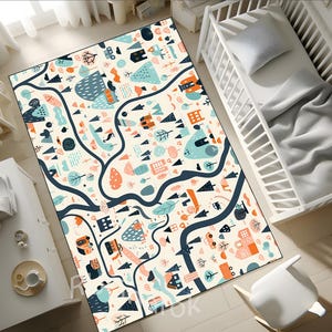 May include: A rectangular area rug with a whimsical town map design. The rug features a cream-colored background with illustrations of houses, trees, and roads in shades of blue, orange, and black. The rug is placed on a wooden floor.