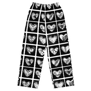 May include: Black and white pajama pants with a repeating pattern of heart-shaped designs. Each heart is contained within a black square and features various embellishments, including spider webs, stitches, and cracks.