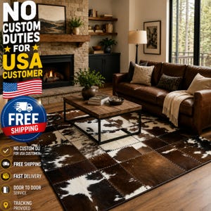 Op de afbeelding: Een rechthoekig koeienvacht tapijt met een patchwork ontwerp in bruin, zwart en wit. Het tapijt ligt op een houten vloer in een woonkamer. De afbeelding toont ook een leren bank, een houten salontafel en een open haard.