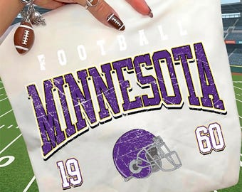 May include: A white t-shirt featuring the word FOOTBALL in small white letters above the word MINNESOTA in large, distressed purple letters with black outlines. Below, a purple football helmet sits between the numbers 19 and 60 in purple.