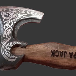 Puede incluir: Una taza de cerámica blanca con un asa negra y el texto "But First, Coffee" en negrita negra. La taza se encuentra sobre un fondo borroso, sugiriendo un ambiente acogedor.