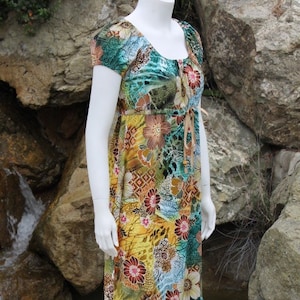 May include: A long, flowing maxi dress with a colorful floral print. The dress has a scoop neck and short sleeves. The fabric is a lightweight, flowing material.