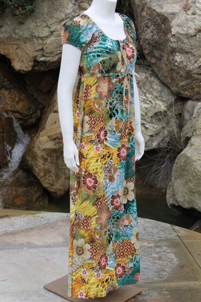 May include: A long, flowing maxi dress with a colorful floral print. The dress has a scoop neck and short sleeves. The fabric is a lightweight, flowing material.