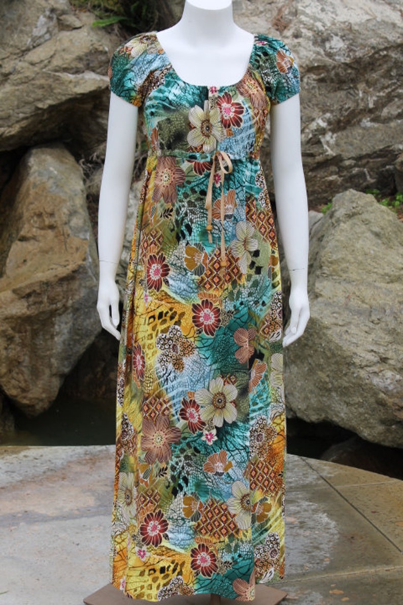 May include: A long, flowing maxi dress with a colorful floral print. The dress has a scoop neckline, short sleeves, and a tie at the waist.