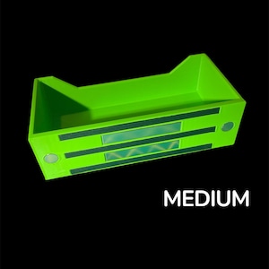 May include: Bright green rectangular storage container with a geometric design on the front. The word "MEDIUM" is printed in white on the bottom of the image. The container has a unique shape with raised sides.