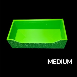 May include: A bright green rectangular container with a textured exterior and the word "MEDIUM" in white text. The container is set against a black background.