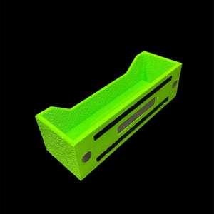 May include: A bright neon green rectangular organizer with a textured surface. The organizer has a tray-like design with raised edges and two black rectangular accents. Two small, round, silver-colored magnets are visible on the side.
