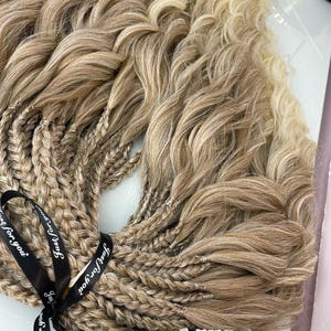 May include: Braided hair extensions in shades of blonde and light brown, tied with a black ribbon that reads "Just for You". The hair has a wavy texture and is arranged in multiple braids.