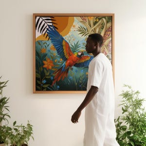 Puede incluir: Una obra de arte enmarcada que representa un guacamayo en vuelo, con plumaje azul, rojo y amarillo. La obra de arte está ambientada sobre un fondo de exuberante vegetación, flores naranjas y un sol amarillo. El marco es de madera marrón claro.