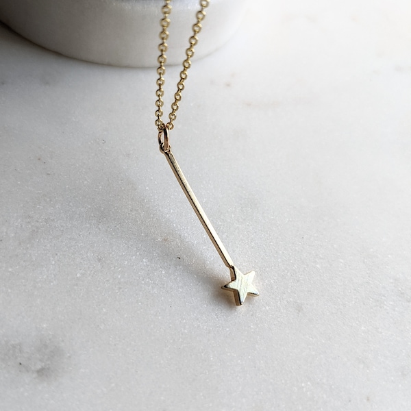 May include: A gold necklace featuring a delicate chain and a star-shaped pendant suspended from a thin, straight bar.