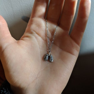May include: A silver chain necklace with a small, detailed pendant shaped like a pair of lungs.