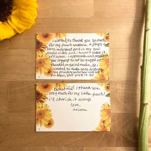 May include: Two handwritten thank you notes with sunflower designs. The first note says, "I wanted to thank you so much for my peach necklace. It plays a very important part in my new music video and I haven't taken it off since. I appreciate and respect your request to not be tagged or thanked on social media. So I wanted to make sure to thank you privately somehow and let you know, your work is so beautiful! I thank you very much for my little peach! I'll cherish it always. Love, Ariana."