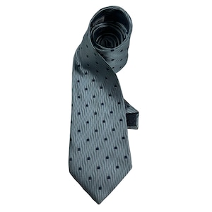 May include: A light blue necktie featuring a repeating pattern of dark blue dots arranged in vertical wavy lines. The tie is rolled at the top, showing a pointed bottom end and a smooth, textured fabric surface with a consistent woven appearance.