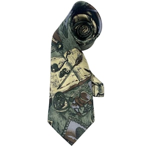 May include: A necktie featuring a sage green background with a printed pattern of vintage writing instruments, including an open book with handwritten script, a quill pen, an inkwell, a pocket watch, and a small framed portrait.