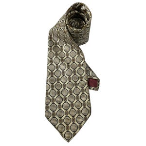 May include: A necktie featuring a repeating geometric pattern of black-outlined octagons on a cream background. Inside each octagon is a small brown and black houndstooth design with a central brown oval. The tie has a dark red fabric label.