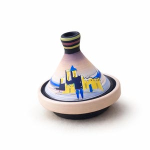 Peut inclure: Un tajine en céramique avec un couvercle conique et une base ronde. Le couvercle est décoré d'une scène peinte d'un château en jaune et bleu. La base est beige avec un bord noir. Le haut du couvercle est noir avec des rayures colorées.