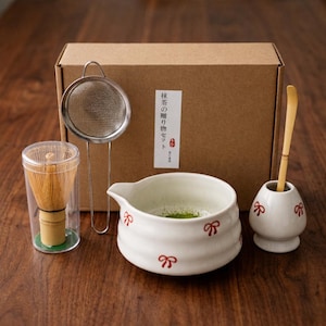 May include: A matcha tea set, comprising a bamboo whisk, a ceramic bowl with red bow detailing, a stainless steel strainer, a bamboo scoop, and a holder. The set is in a brown cardboard box with Japanese text.