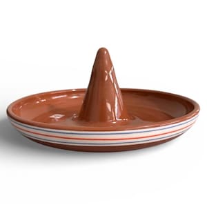 May include: A brown ceramic ring holder with a conical center and a wide, shallow dish base. The base is decorated with horizontal stripes of red, white, and blue. The ring holder is designed to hold rings.