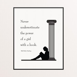 May include: Black and white framed print featuring a silhouette of a person reading a book next to a classical column. The text reads: "Never underestimate the power of a girl with a book." Quote by Ruth Bader Ginsburg.
