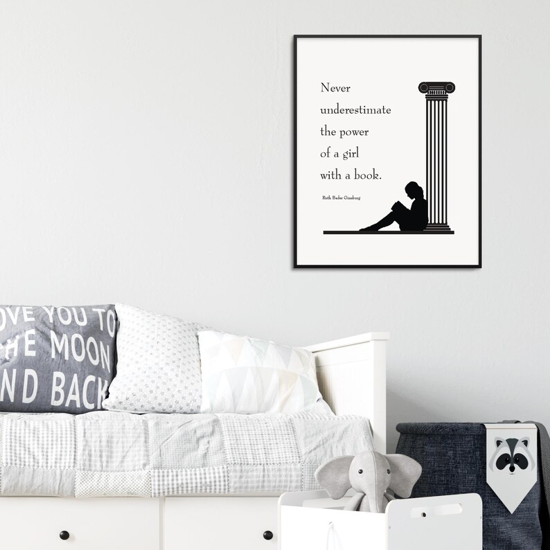 May include: A framed black and white print with the quote, "Never underestimate the power of a girl with a book." The print features a silhouette of a person reading next to a column. The print is displayed above a bed.