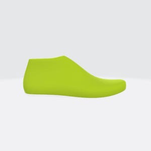 Puede incluir: Una horma de zapato verde lima, una forma utilizada en la fabricación de calzado, se muestra sobre un fondo blanco. La horma es un modelo sólido tridimensional de un pie, utilizado para dar forma a los zapatos.