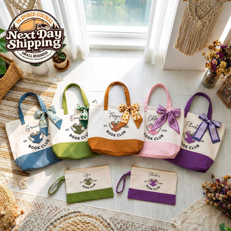 A collection of colorful tote bags and a small bag, all with the text "Book Club" printed on them, arranged on a wooden floor near a window.