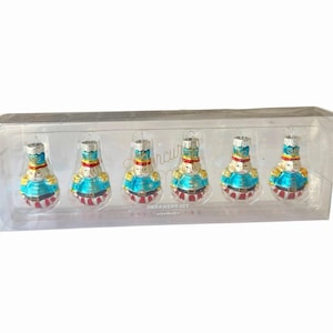 May include: A set of six glass nutcracker ornaments in a clear plastic display box. Each ornament features a blue jacket, red and white striped trousers, a gold hat, and a painted face. The text Ornament Set is printed on the box packaging.