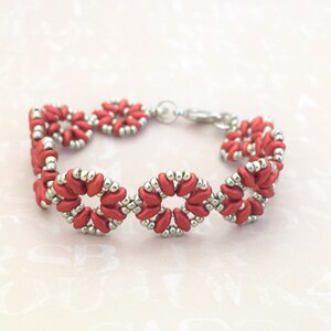 May include: A red and silver beaded bracelet with a flower design. The bracelet is made with small, round beads and has a clasp closure.