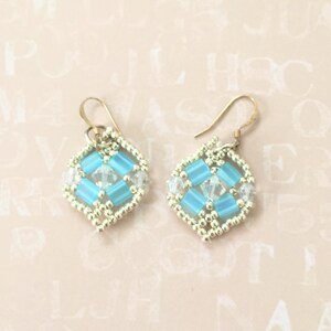 May include: A pair of gold earrings with a blue and white geometric design. The earrings are made with small beads and have a dangling design.