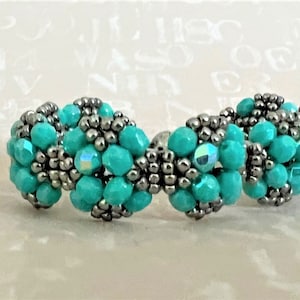 May include: A turquoise and silver beaded bracelet with a woven design.