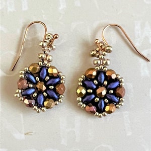 May include: A pair of gold tone earrings with a blue and gold beaded design. The earrings are dangle style with a small loop at the top.