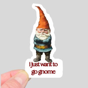 May include: A sticker featuring a grumpy garden gnome with an orange hat, blue coat, and white beard. The sticker has the text "i just want to go gnome" in red. The gnome is standing with arms crossed.