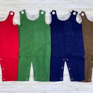 May include: Four pairs of corduroy overalls for babies in red, green, blue, and brown.
