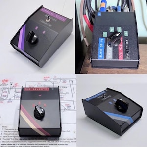 May include: A black metal audio signal switcher box featuring a central rotary knob, a toggle switch, and colorful adhesive labels with text including Parallel Block, The Selector, Bluno Drive, Prince, and Valley Dr, presented in four views.