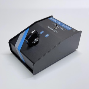 May include: Black electronic device with a knob and switch. The device has blue and gray stripes and the text "PARALLEL BLOCK" and "ISOLATED". The knob is black and silver. The switch has three settings: "PARALLEL", "BLOCK", and "ISOLATED".