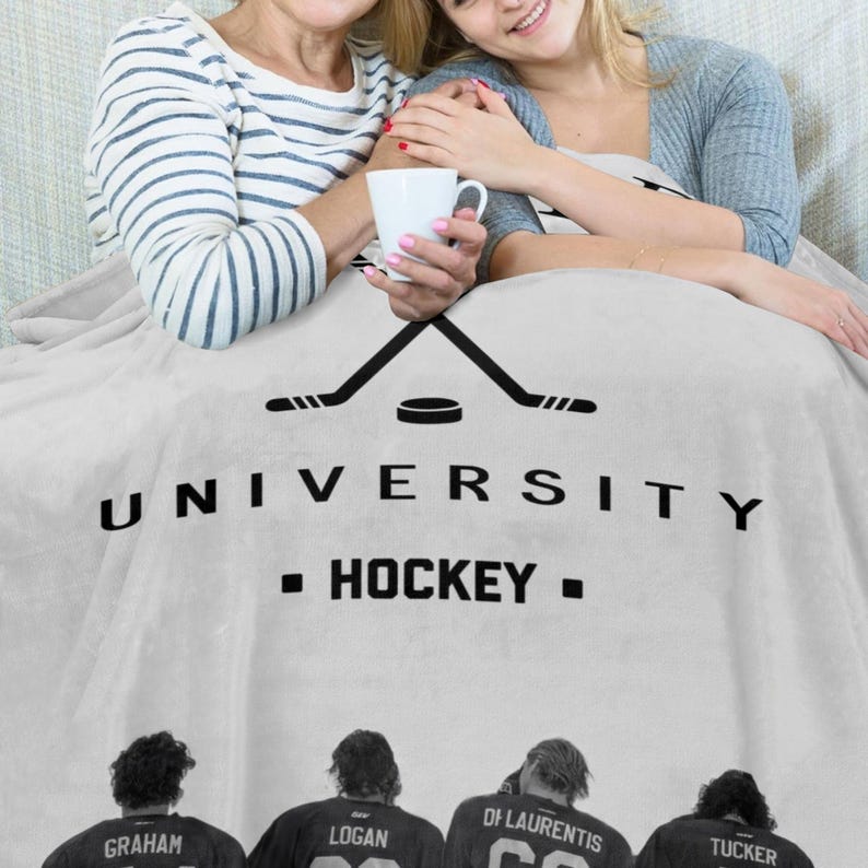 Pu&ograve; includere: Una coperta in pile grigio chiaro con una grafica nera di due bastoni da hockey incrociati e un disco sopra il testo UNIVERSITY HOCKEY. Sotto il testo ci sono quattro giocatori di hockey con maglie recanti i nomi GRAHAM, LOGAN, DI LAURENTIS e TUCKER.