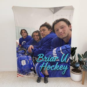Pu&ograve; includere: Una coperta rettangolare in pile con una fotografia stampata di quattro persone che indossano maglie ed equipaggiamento da hockey blu. Il testo "Briar U Hockey" &egrave; stampato in un carattere corsivo azzurro nella parte inferiore della coperta.