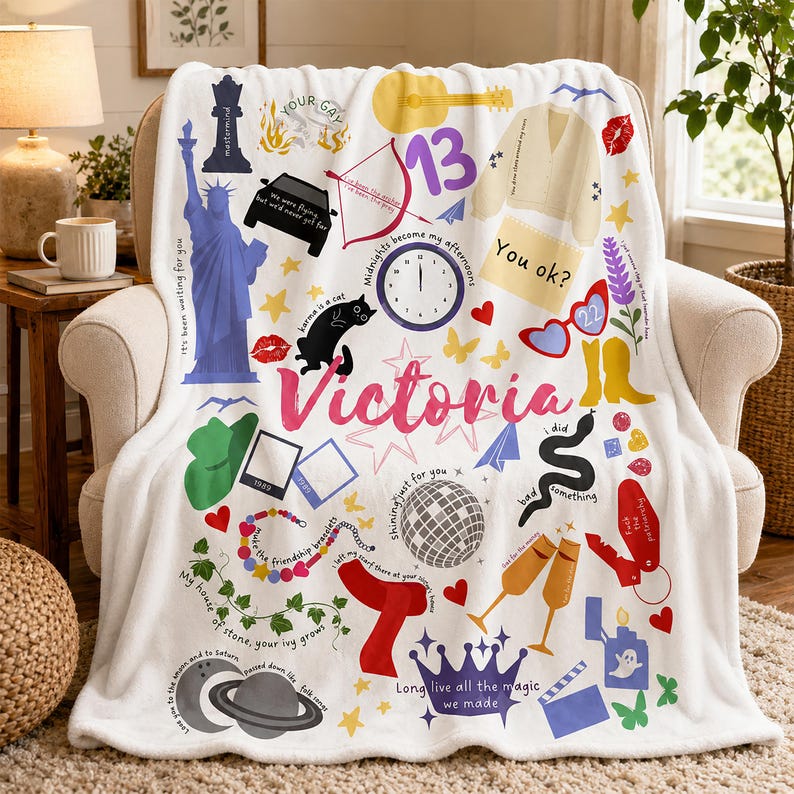 May include: White fleece blanket with colorful illustrations, including a guitar, a clock, a car, and the name "Victoria" in pink. The blanket has various text elements.